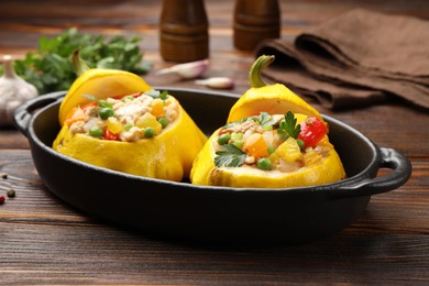 Photo of Tasty stuffed pattypan squashes in baking dish on wooden table, closeup