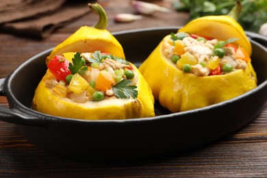 Photo of Tasty stuffed pattypan squashes in baking dish on wooden table, closeup