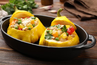 Photo of Tasty stuffed pattypan squashes in baking dish on wooden table, closeup