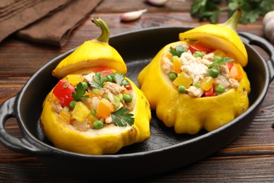 Photo of Tasty stuffed pattypan squashes in baking dish on wooden table, closeup