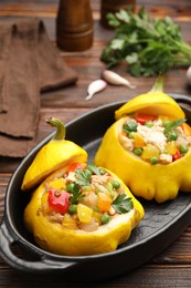 Photo of Tasty stuffed pattypan squashes in baking dish on wooden table, closeup