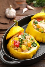 Photo of Tasty stuffed pattypan squashes in baking dish on wooden table, closeup
