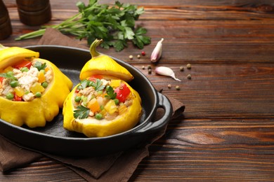 Photo of Tasty stuffed pattypan squashes in baking dish on wooden table, closeup. Space for text