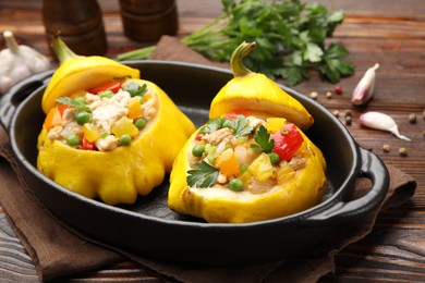 Photo of Tasty stuffed pattypan squashes in baking dish on wooden table, closeup