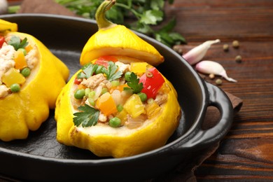 Photo of Tasty stuffed pattypan squashes in baking dish on wooden table, closeup