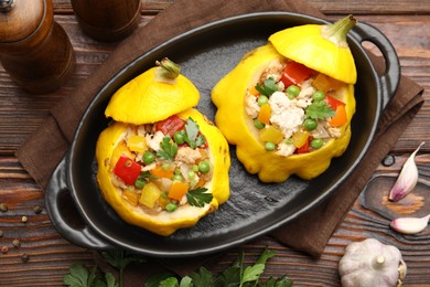 Photo of Tasty stuffed pattypan squashes in baking dish on wooden table, flat lay
