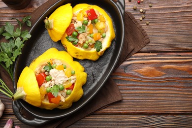 Photo of Tasty stuffed pattypan squashes in baking dish on wooden table, flat lay
