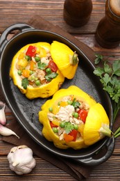 Photo of Tasty stuffed pattypan squashes in baking dish on wooden table, flat lay