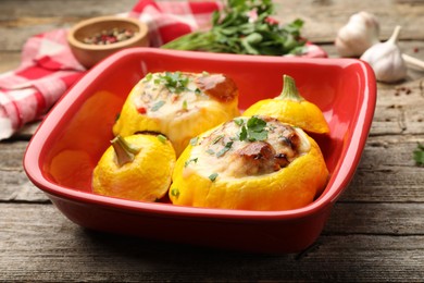 Photo of Tasty stuffed pattypan squashes in baking dish on wooden table, closeup