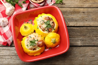 Photo of Tasty stuffed pattypan squashes in baking dish on wooden table, flat lay. Space for text
