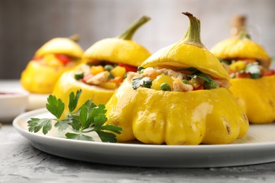 Photo of Tasty stuffed pattypan squashes on grey textured table, closeup