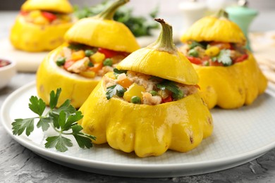 Photo of Tasty stuffed pattypan squashes on grey textured table, closeup