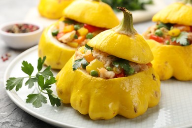 Photo of Tasty stuffed pattypan squashes on grey textured table, closeup