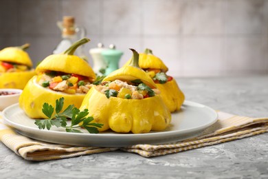 Photo of Tasty stuffed pattypan squashes on grey textured table, closeup