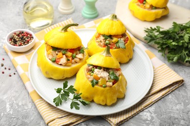 Photo of Tasty stuffed pattypan squashes on grey textured table, closeup