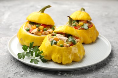 Photo of Tasty stuffed pattypan squashes on grey textured table, closeup