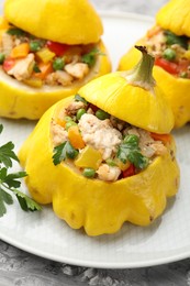 Photo of Tasty stuffed pattypan squashes on grey textured table, closeup