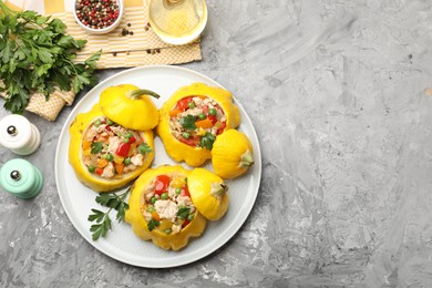 Photo of Tasty stuffed pattypan squashes and spices on grey textured table, flat lay. Space for text