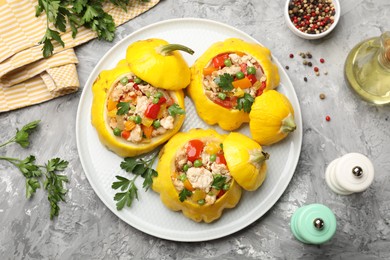 Photo of Tasty stuffed pattypan squashes and spices on grey textured table, flat lay