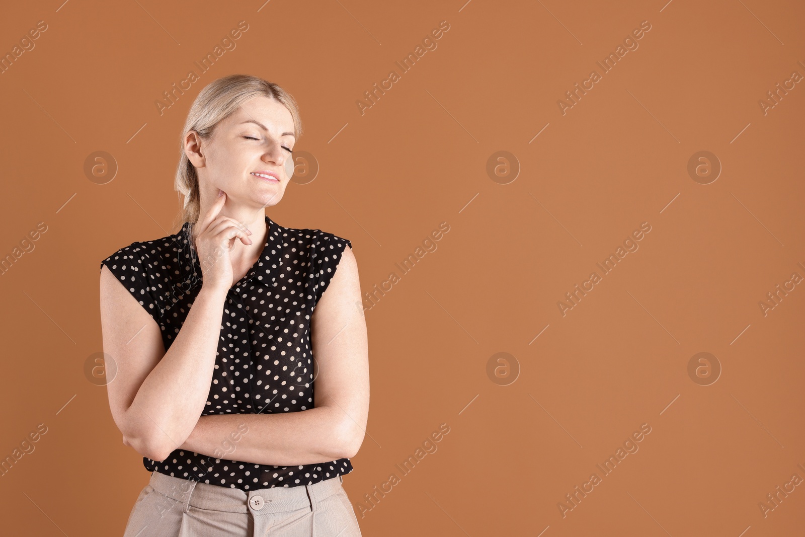 Dreams come true. Woman thinking about something on brown background, space for text Photo of Dreams come true. Woman thinking about something on brown background, space for text