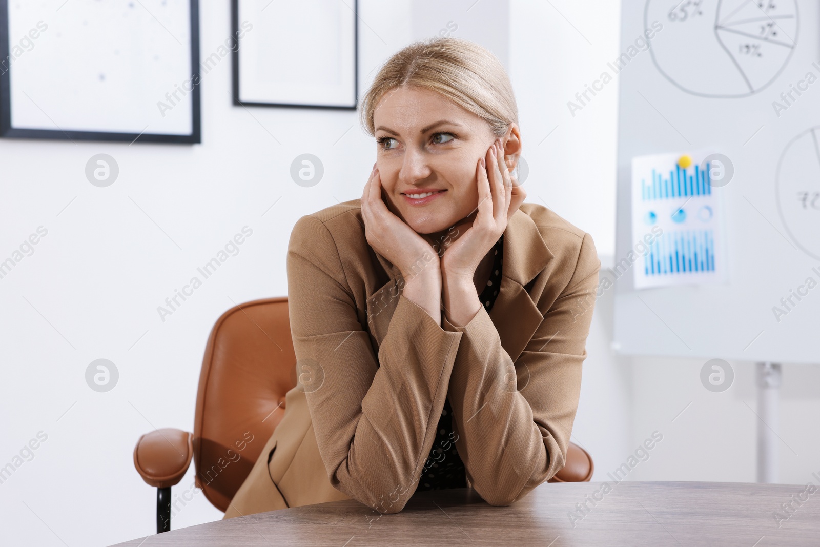 Dreams come true. Happy woman thinking about something at wooden table indoors Photo of Dreams come true. Happy woman thinking about something at wooden table indoors