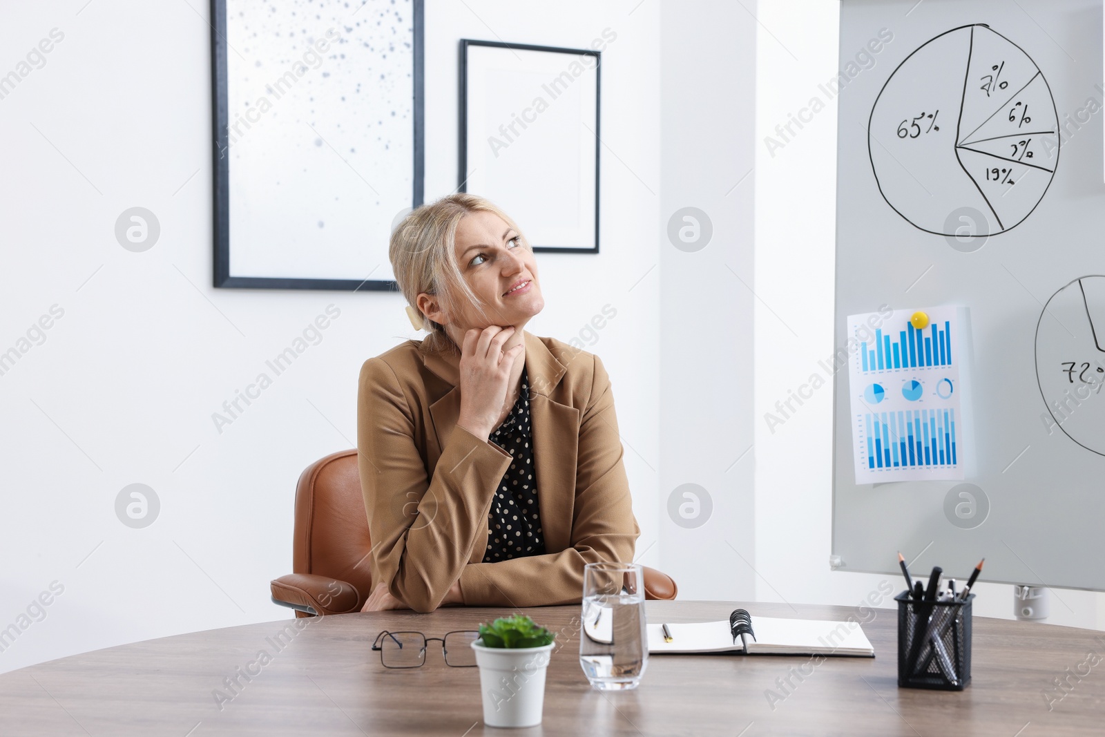 Dreams come true. Woman thinking about something at wooden table indoors Photo of Dreams come true. Woman thinking about something at wooden table indoors