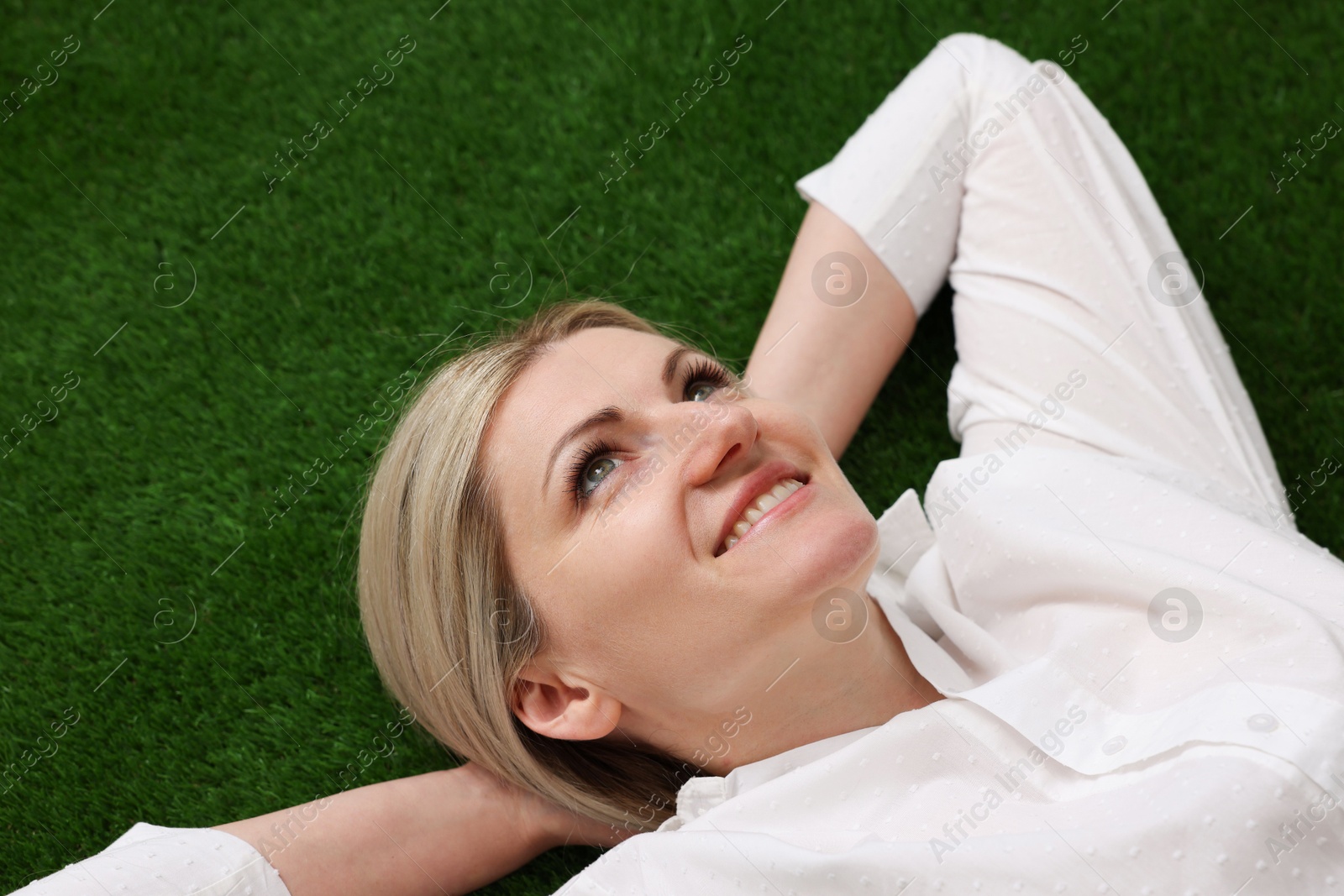 Dreams come true. Woman thinking about something on green grass outdoors, above view Photo of Dreams come true. Woman thinking about something on green grass outdoors, above view