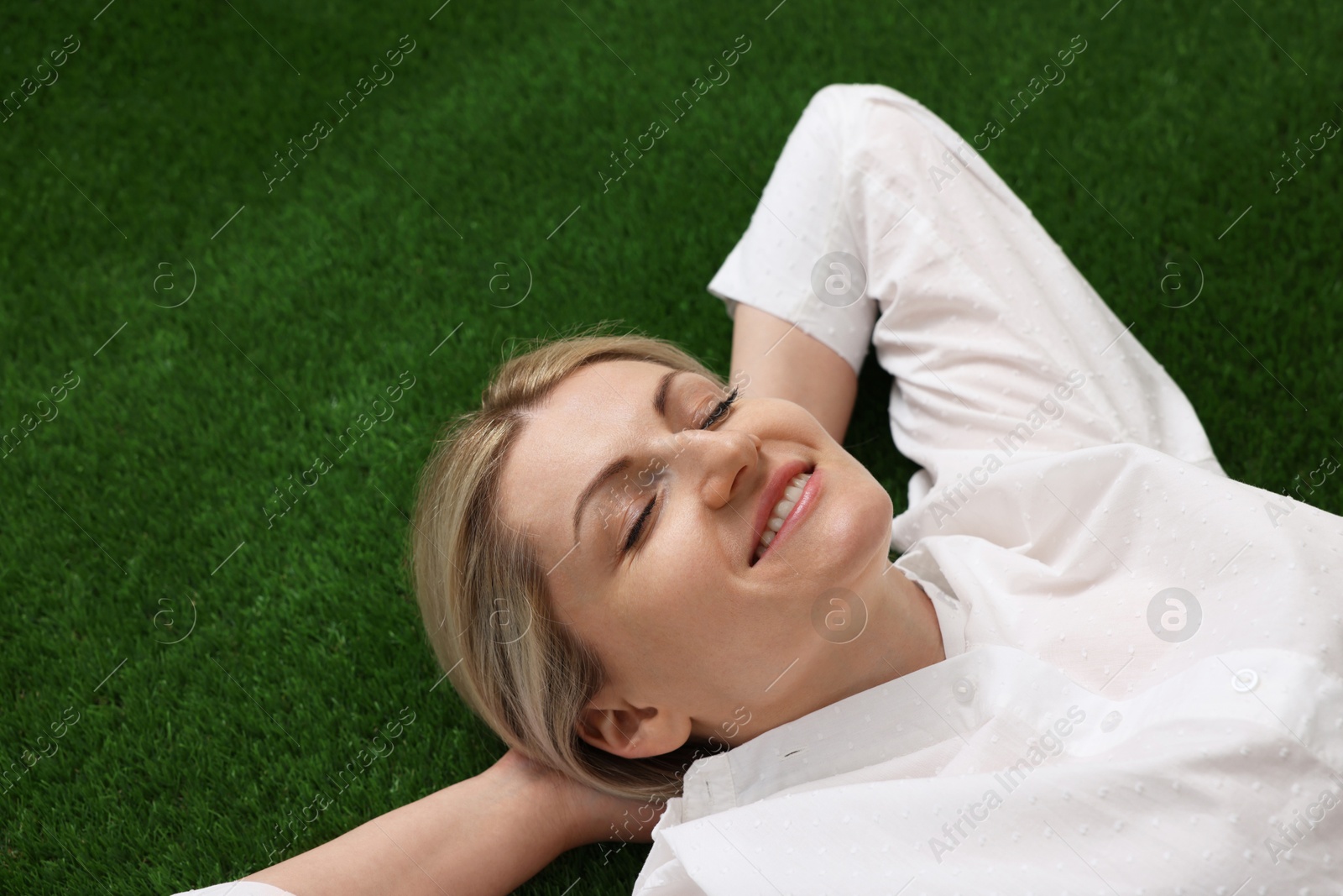 Dreams come true. Woman thinking about something on green grass outdoors, above view Photo of Dreams come true. Woman thinking about something on green grass outdoors, above view