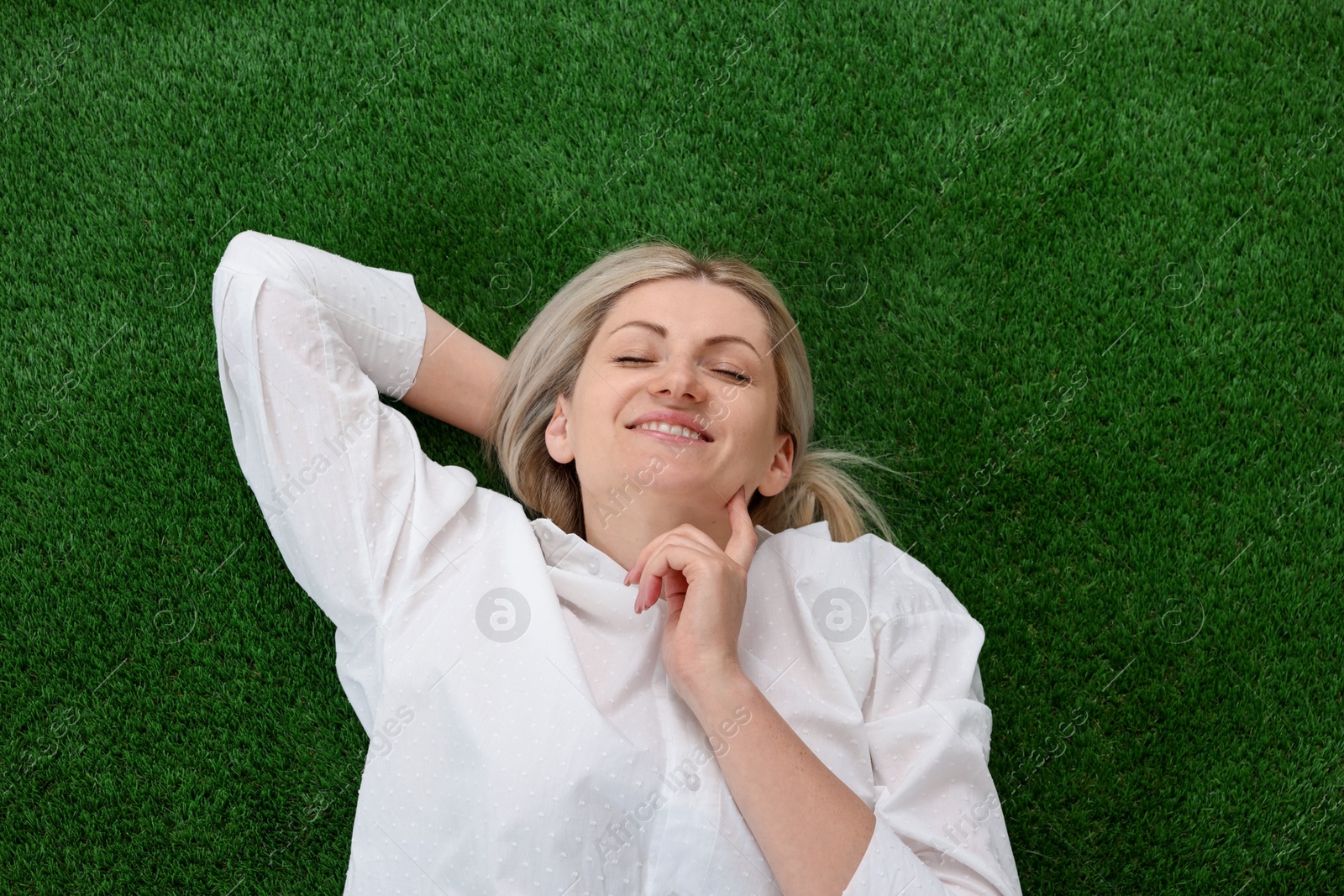 Dreams come true. Woman thinking about something on green grass outdoors, top view Photo of Dreams come true. Woman thinking about something on green grass outdoors, top view