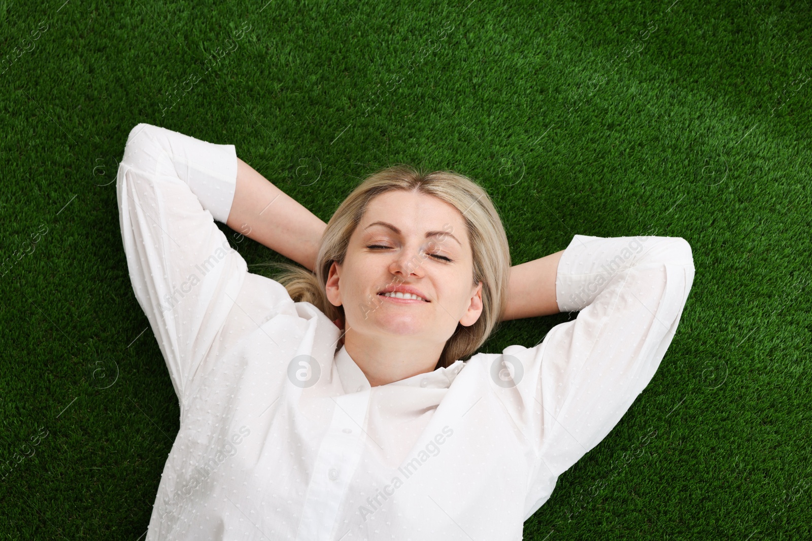 Dreams come true. Woman thinking about something on green grass outdoors, top view Photo of Dreams come true. Woman thinking about something on green grass outdoors, top view