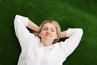 Photo of Dreams come true. Woman thinking about something on green grass outdoors, top view