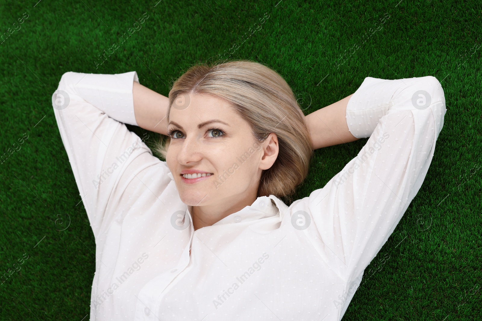 Dreams come true. Woman thinking about something on green grass outdoors, top view Photo of Dreams come true. Woman thinking about something on green grass outdoors, top view