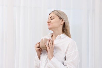 Photo of Dreams come true. Woman with cup of drink thinking about something at home
