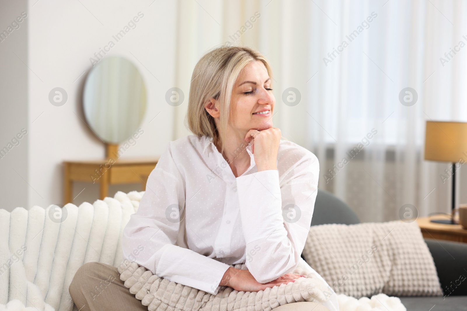 Dreams come true. Woman with pillow thinking about something on sofa at home Photo of Dreams come true. Woman with pillow thinking about something on sofa at home
