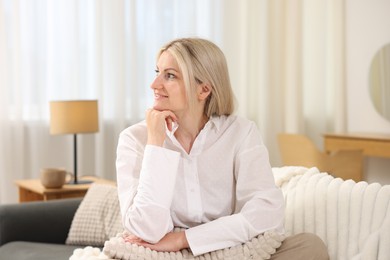 Photo of Dreams come true. Woman with pillow thinking about something on sofa at home