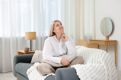 Photo of Dreams come true. Woman with pillow thinking about something on sofa at home