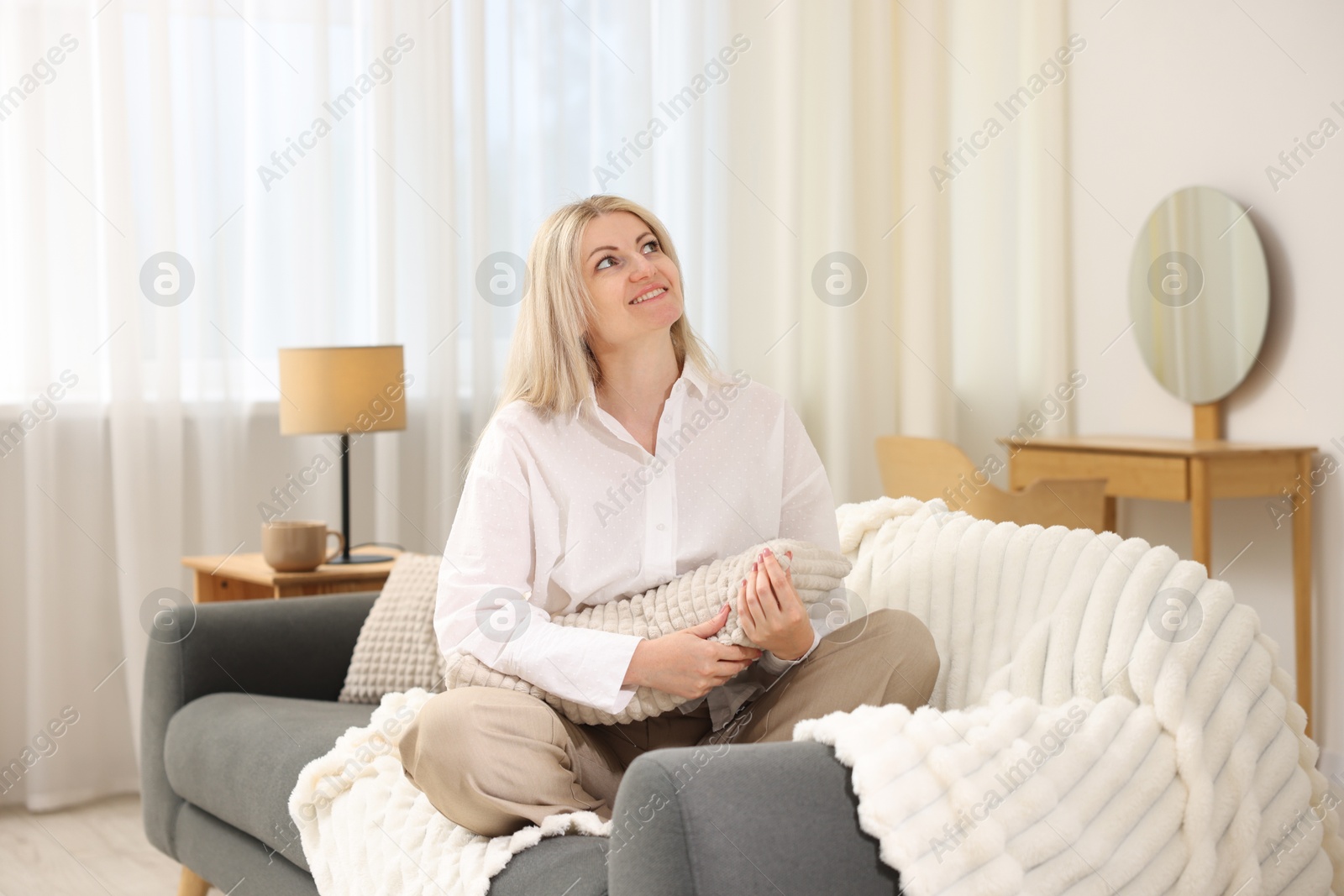 Dreams come true. Woman with pillow thinking about something on sofa at home Photo of Dreams come true. Woman with pillow thinking about something on sofa at home