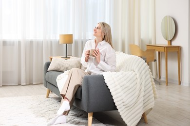 Photo of Dreams come true. Woman with cup of drink thinking about something on sofa at home