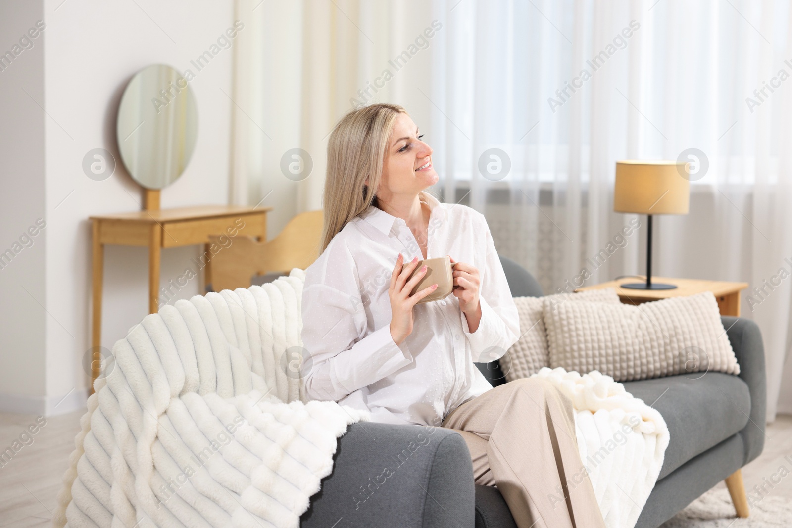 Dreams come true. Woman with cup of drink thinking about something on sofa at home Photo of Dreams come true. Woman with cup of drink thinking about something on sofa at home