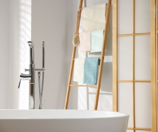 Photo of Fresh clean waffle towels drying on rack in bathroom
