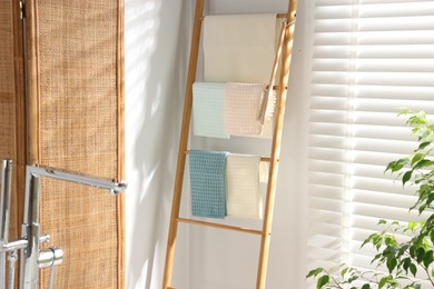 Photo of Fresh clean waffle towels drying on rack in bathroom