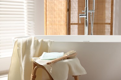 Photo of Clean waffle towels and brush on table near bath indoors