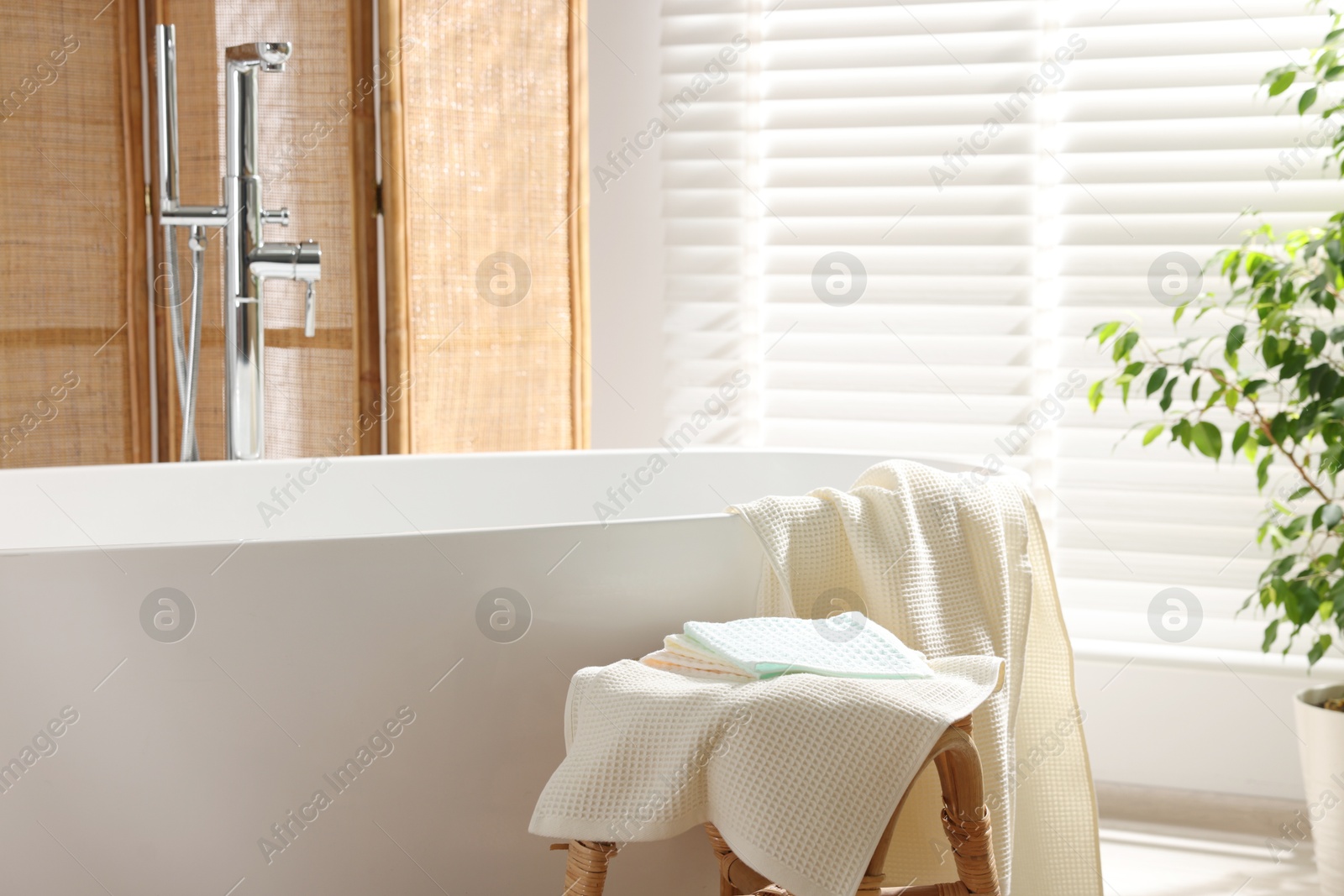 Photo of Clean waffle towels on table near bath indoors