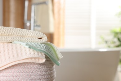 Photo of Clean waffle towels in basket near bath indoors, closeup. Space for text