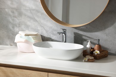 Photo of Clean waffle towels, plumeria flowers and cosmetic products on counter in bathroom