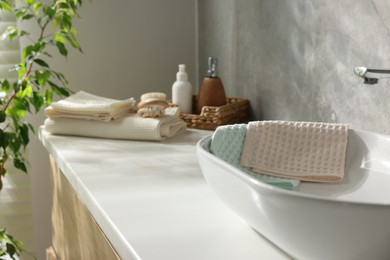 Photo of Clean waffle towels, brush and cosmetic products on counter in bathroom, selective focus