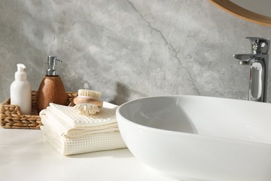 Photo of Clean waffle towels, brush and cosmetic products on counter in bathroom