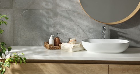 Photo of Clean waffle towels, brush and cosmetic products on counter in bathroom