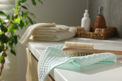 Photo of Clean waffle towels, brush and cosmetic products on counter in bathroom, selective focus