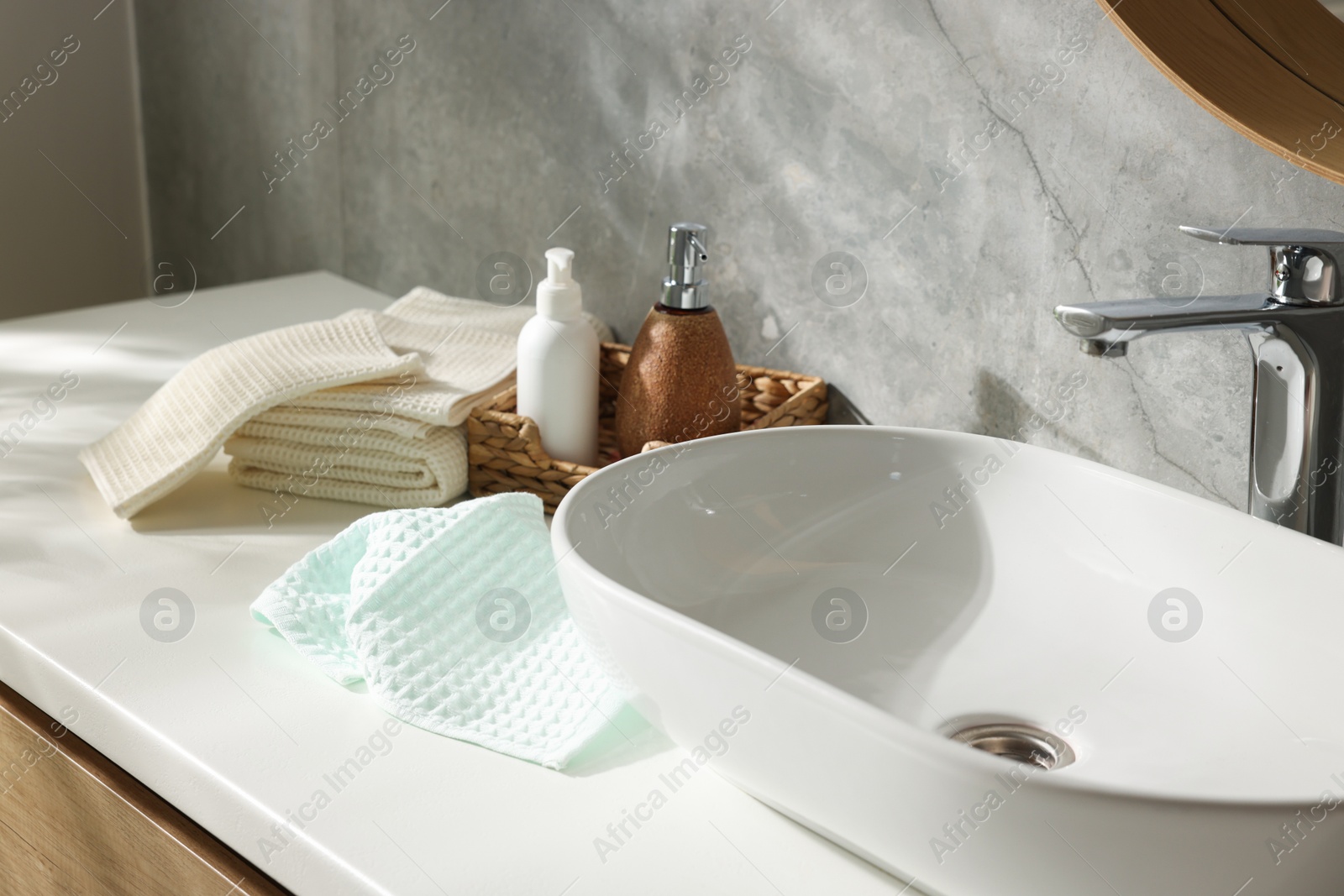 Photo of Clean waffle towels and cosmetic products on counter in bathroom